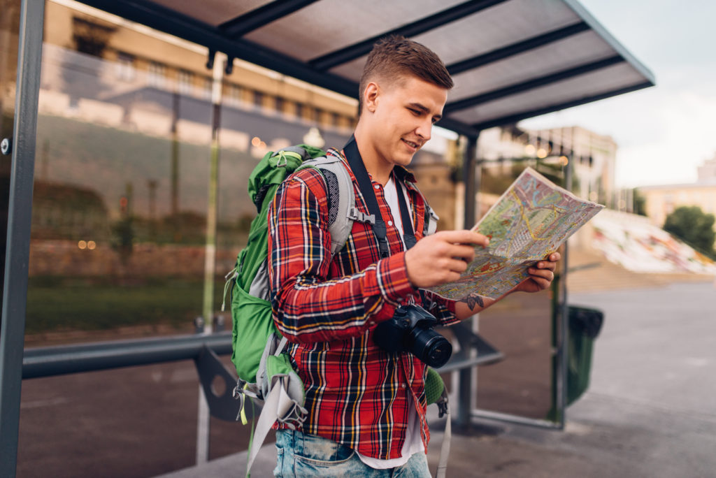 Male tourist with backpack at bus stop